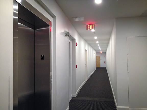 A long hallway with a red exit sign at the end.